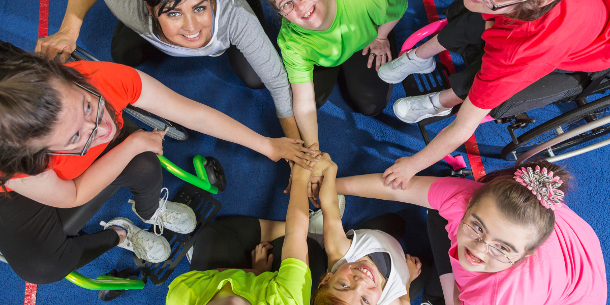 Children with special education needs joining hands with a teacher or support worker