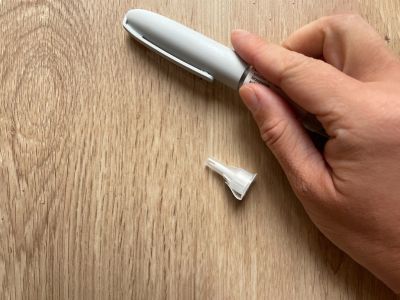 A photo of a hand holding a pen-syringe used for injecting doses of tirzepatide